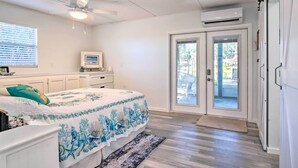 A bedroom with a bed, a ceiling fan, a TV, and a sliding glass door leading to an outdoor area.
