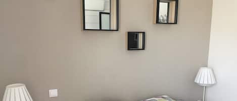 Un dormitorio con una cama, dos lámparas de noche y tres espejos en la pared.