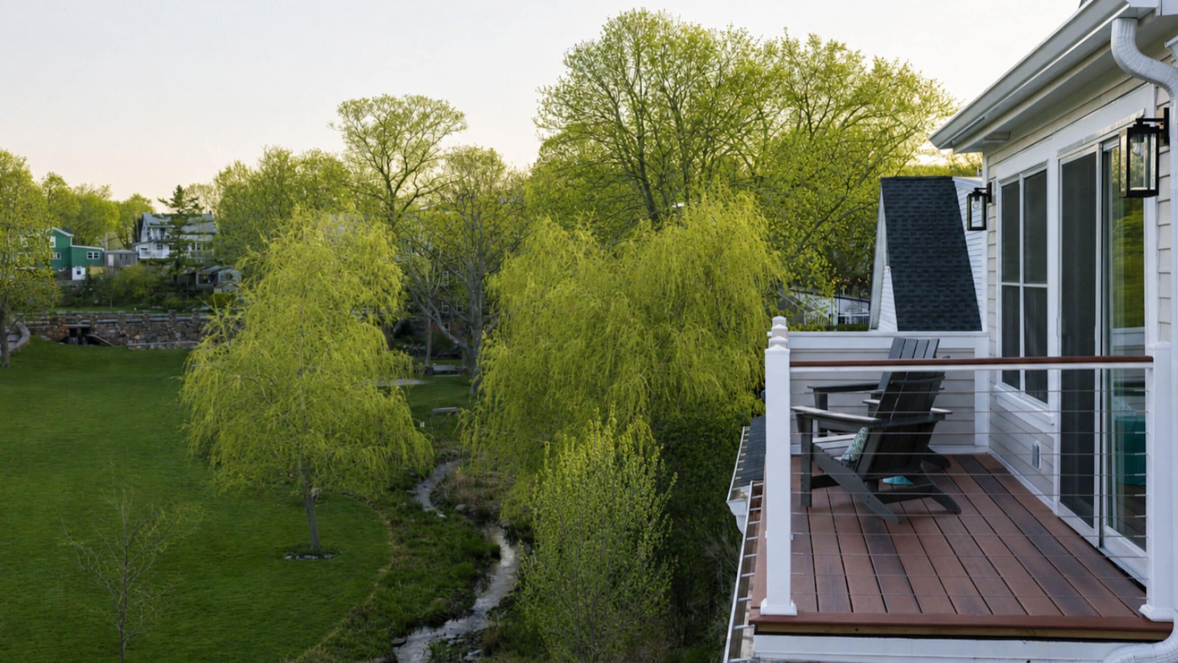 Eine Terrasse mit Gartenmöbeln, ein Kiesweg und eine Rasenfläche mit Bäumen.