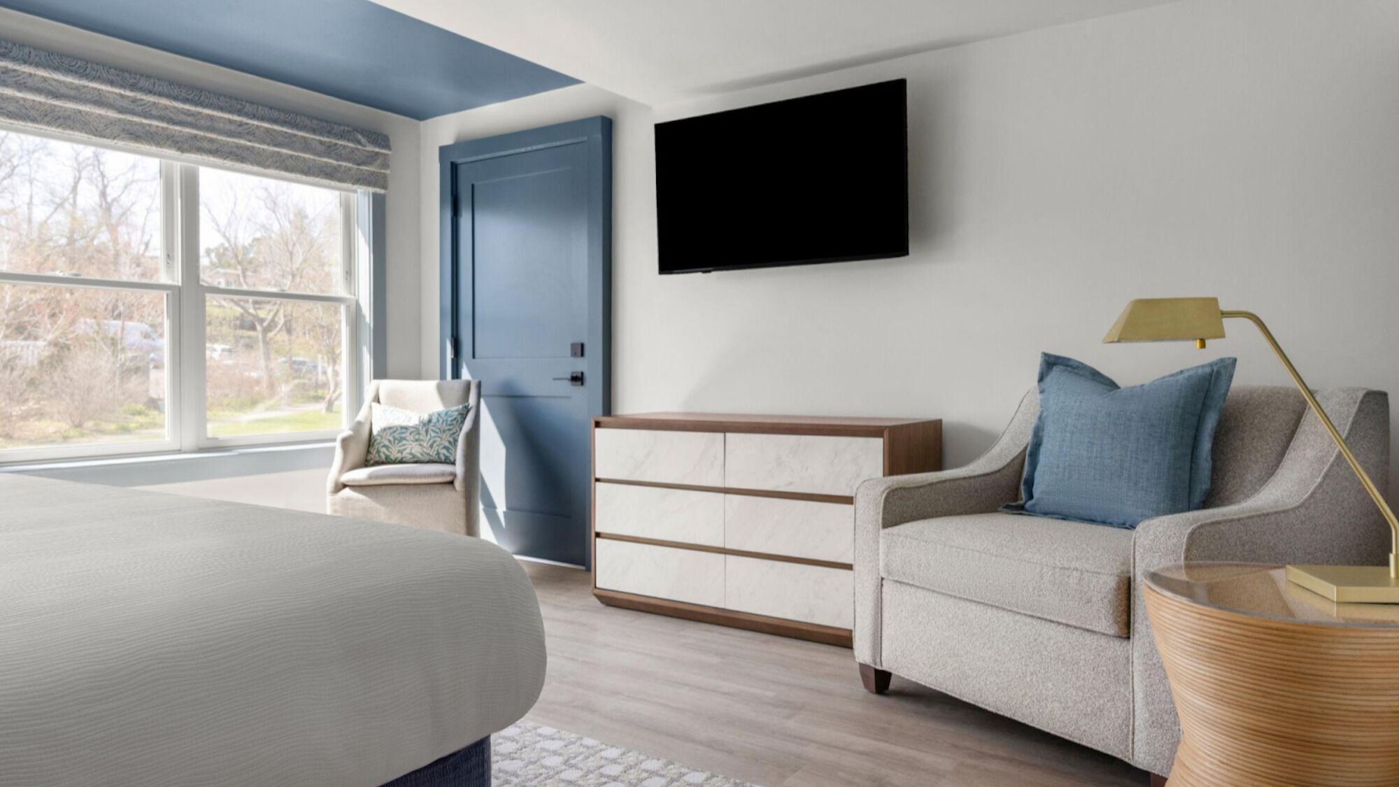 A bedroom with a bed, a dresser, a chair, a television, and a lamp.
