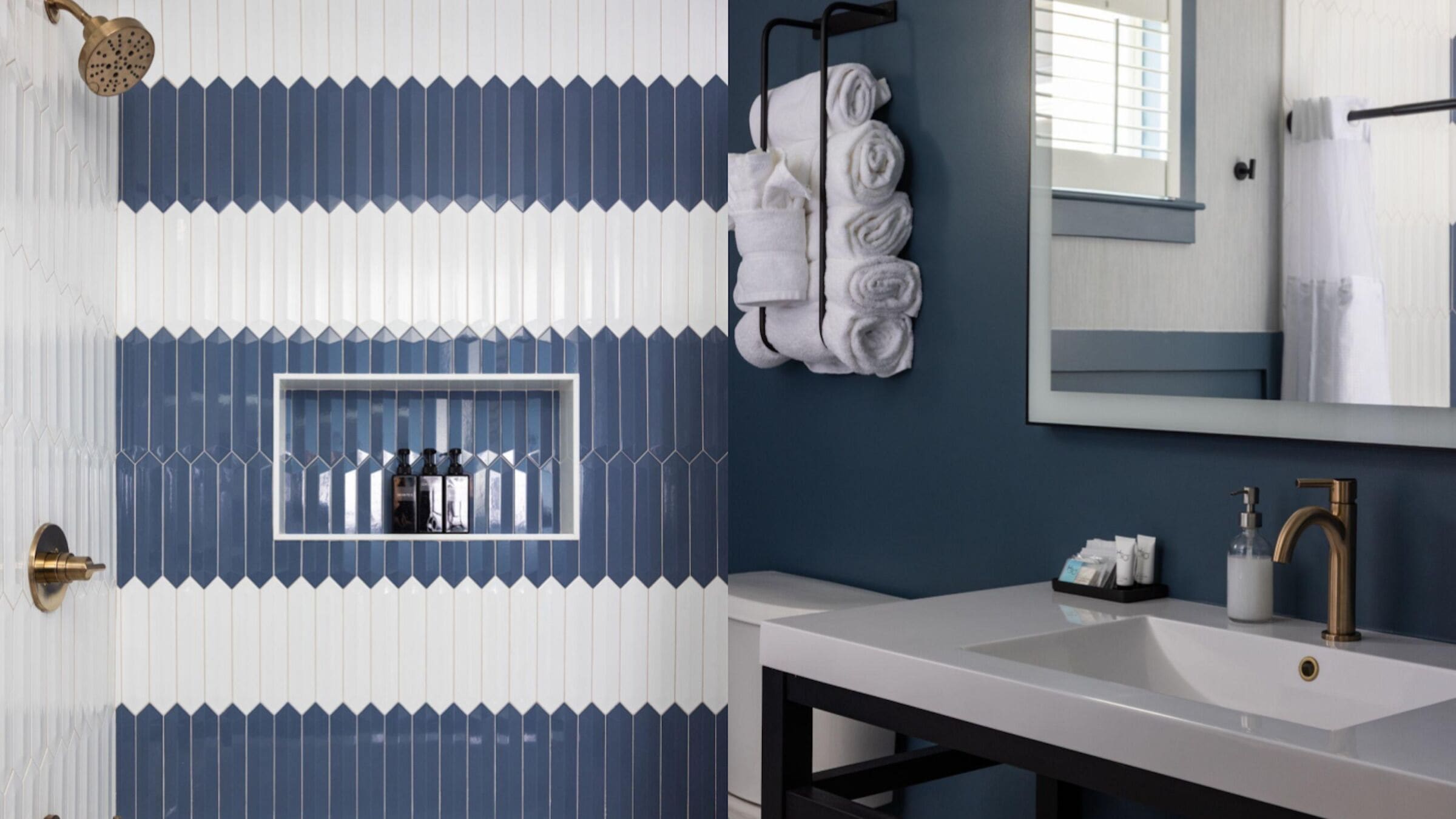 Une salle de bain avec un lavabo blanc, un miroir, un porte-serviettes avec des serviettes et une pomme de douche.