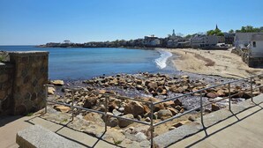 A coastal view with a stone bench, clear sky, and a distant church. - The Cove at Rockport Hotel (Rockport)