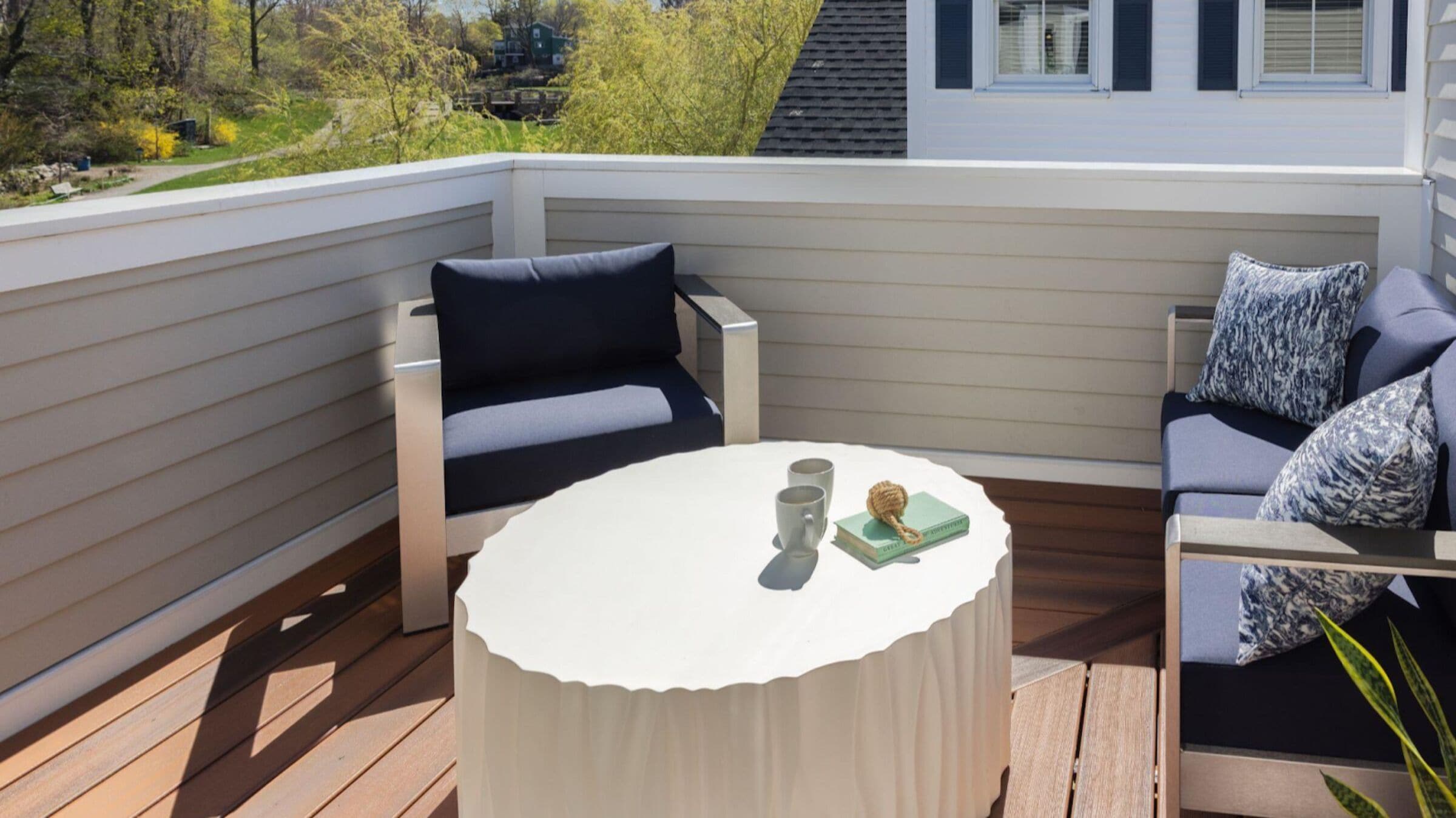 Une terrasse avec une table ronde, deux chaises et un canapé.