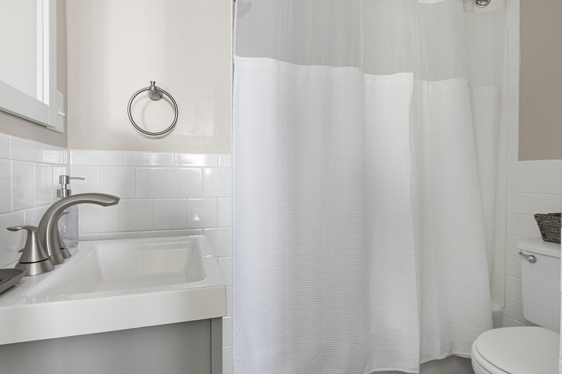 A bathroom with a white sink, a toilet, and a shower curtain.