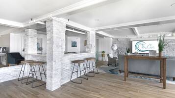 Un amplio salón con una pared de ladrillo blanco, piso de madera y una zona de bar con taburetes.