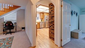 Un interior de vivienda con cocina, comedor y una escalera que sube a un nivel superior.