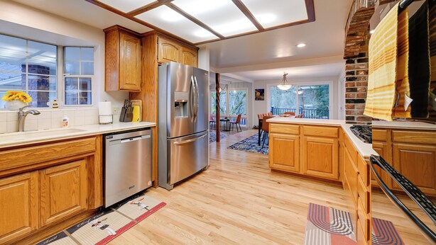 Una cocina moderna con armarios de madera, electrodomésticos de acero inoxidable y un amplio ventanal.