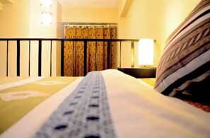 Enjoy a restful stay in this cozy room featuring a comfortable bed and a balcony with a railing.