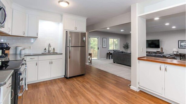 Una cocina moderna con armarios blancos, electrodomésticos de acero inoxidable y suelo de madera.