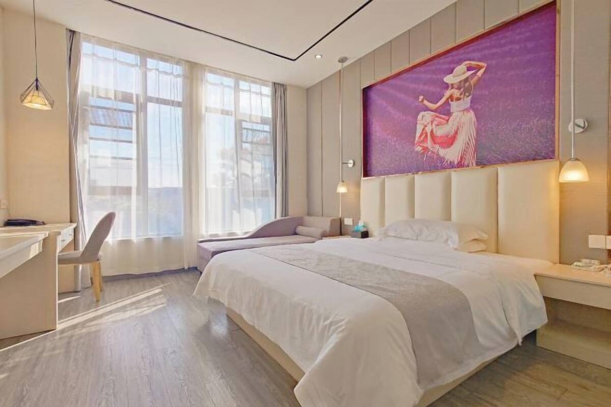 Een moderne hotelkamer met een groot bed, een bureau en een groot raam.