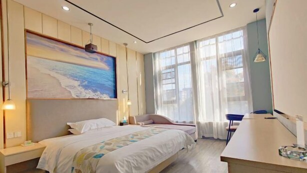 Une chambre à coucher avec un lit, des tables de chevet, un bureau, une grande fenêtre et un tableau au mur.