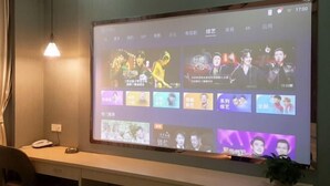 Un écran de projection affiche différents contenus sur un mur, avec un bureau et une chaise placés devant.