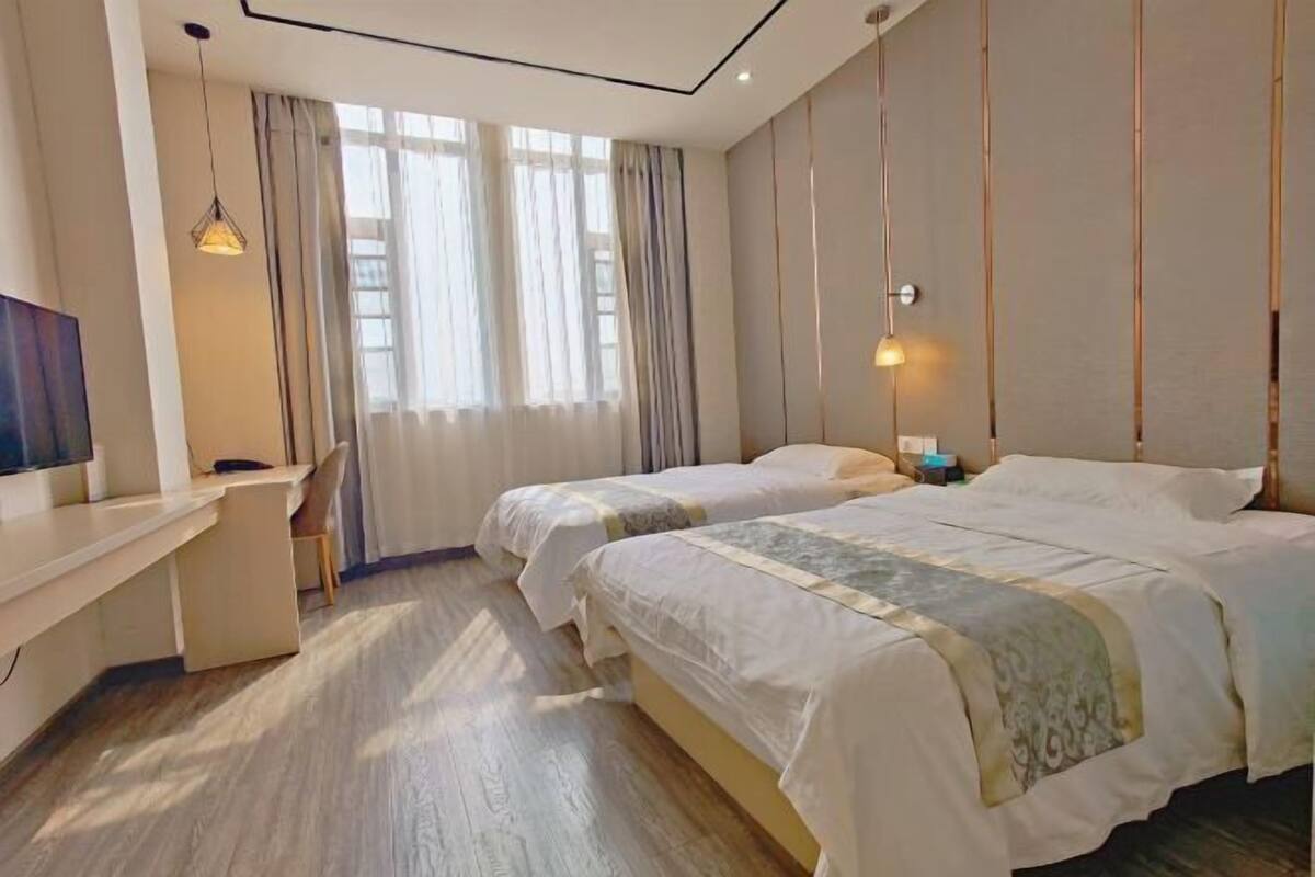 Een hotelkamer met twee bedden, een bureau, een stoel en een televisie.