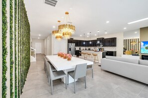 Enjoy meals at the large dining table surrounded by comfortable chairs and a stylish chandelier.