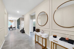 Experience the perfect blend of functionality and elegance in this stylish space, featuring a console table, oval mirror, and chandelier.