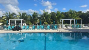 A swimming pool with lounge chairs and umbrellas, surrounded by palm trees and a clear sky. - Tropical Getaway in the heart of Key Largo (Key Largo)