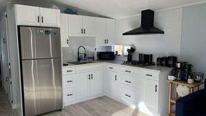 A modern kitchen with white cabinets, stainless steel appliances, and a black range hood. - Tropical Getaway in the heart of Key Largo (Key Largo)