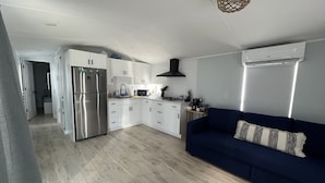 A modern kitchen with white cabinets, a stainless steel refrigerator, and a blue sofa in the living area. - Tropical Getaway in the heart of Key Largo (Key Largo)