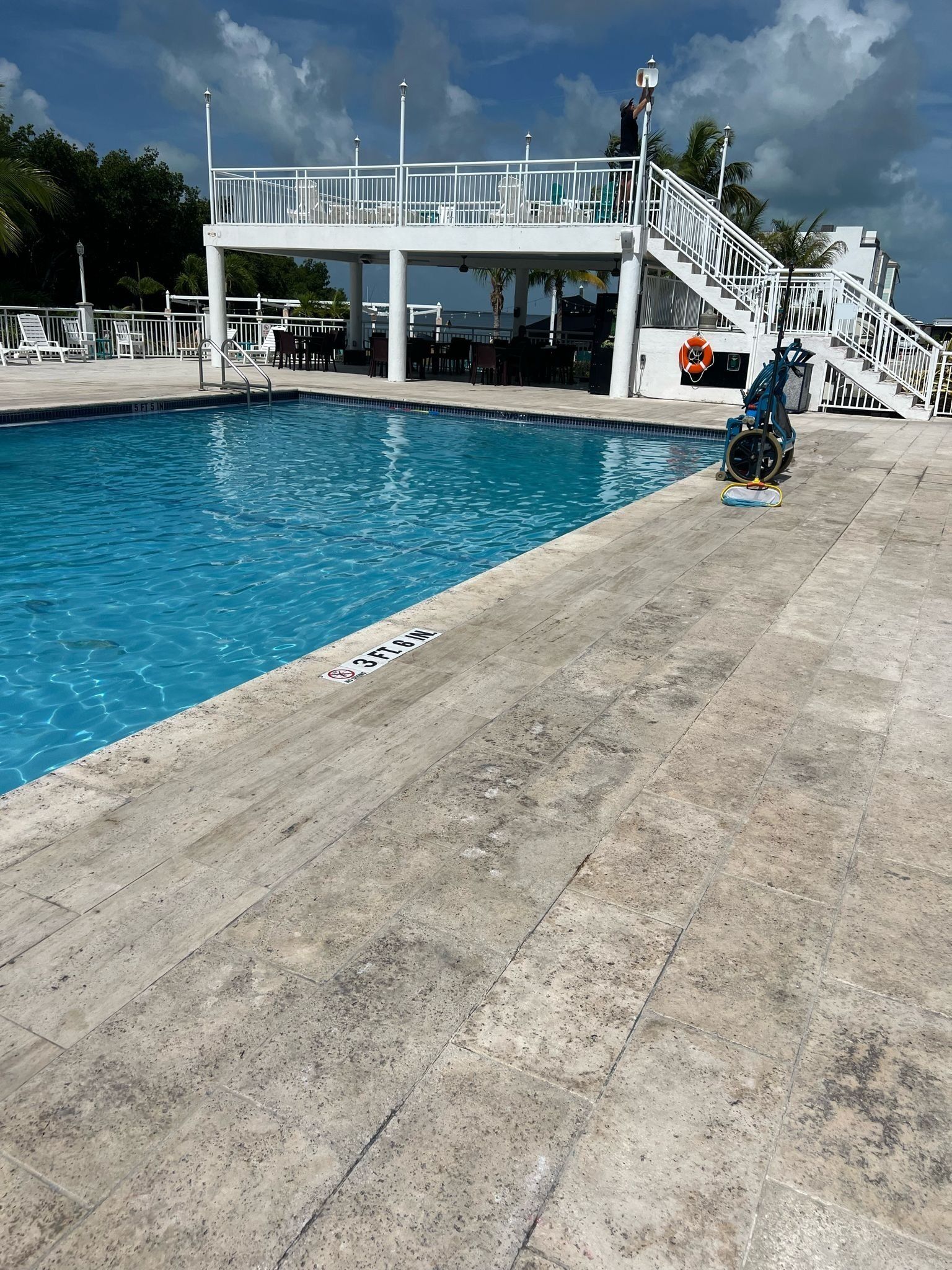 A swimming pool with a lifeguard tower, a covered seating area, and a lifebuoy.