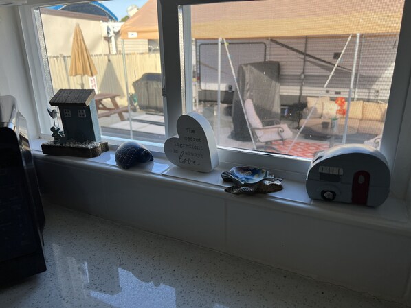 A window sill with various decorative items including a house model, a heart-shaped sign, and a snail figurine. - Tropical Tiny Home Getaway in Key Largo (Key Largo)