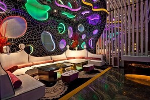 A modern lounge area with a geometric wall design, seating arrangements, and a reflective floor. - Hengda Hotel (Meishan)