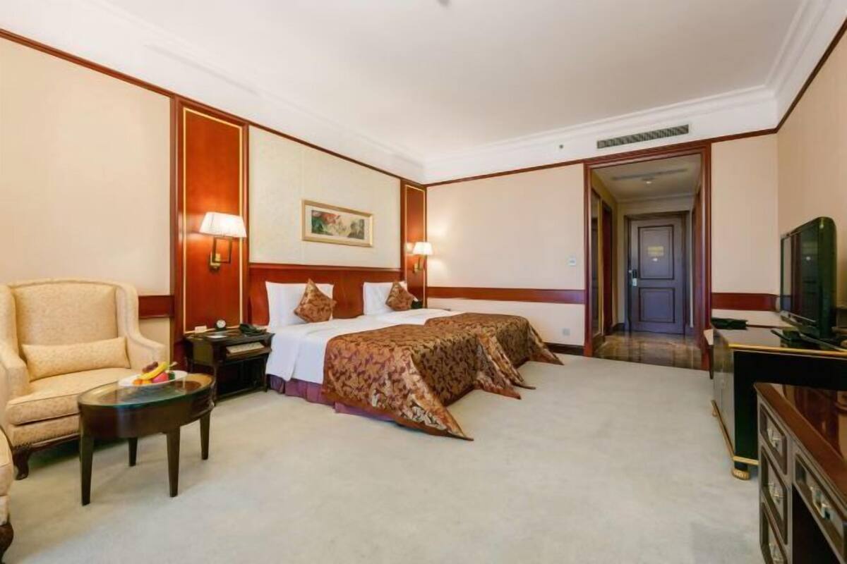Habitación de hotel con dos camas, un sofá, un escritorio y un televisor.