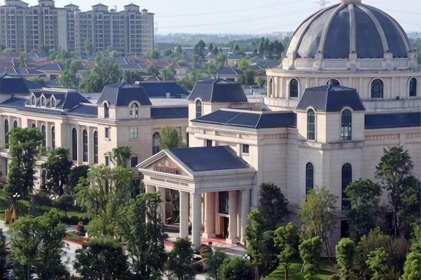 A large building with a dome and multiple smaller structures, surrounded by trees. - Hengda Hotel (Meishan)