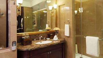 A bathroom with a marble vanity, a large mirror, a glass shower enclosure, and a towel rack.