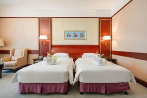 Une chambre d’hôtel avec deux lits, une chaise, une lampe et un tableau encadré au mur.
