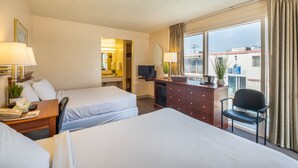 A hotel room with two beds, a desk with a lamp, a dresser, a chair, and a TV. - Tahiti Inn  (Ocean City)