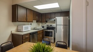 A compact kitchen with wooden cabinets, a microwave, a stove, and a refrigerator. - Tahiti Inn  (Ocean City)