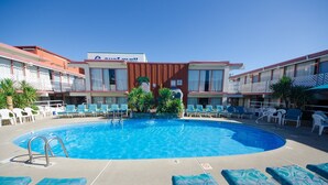 A hotel with a swimming pool, lounge chairs, and a sign indicating a 'Sea View' room. - Tahiti Inn  (Ocean City)
