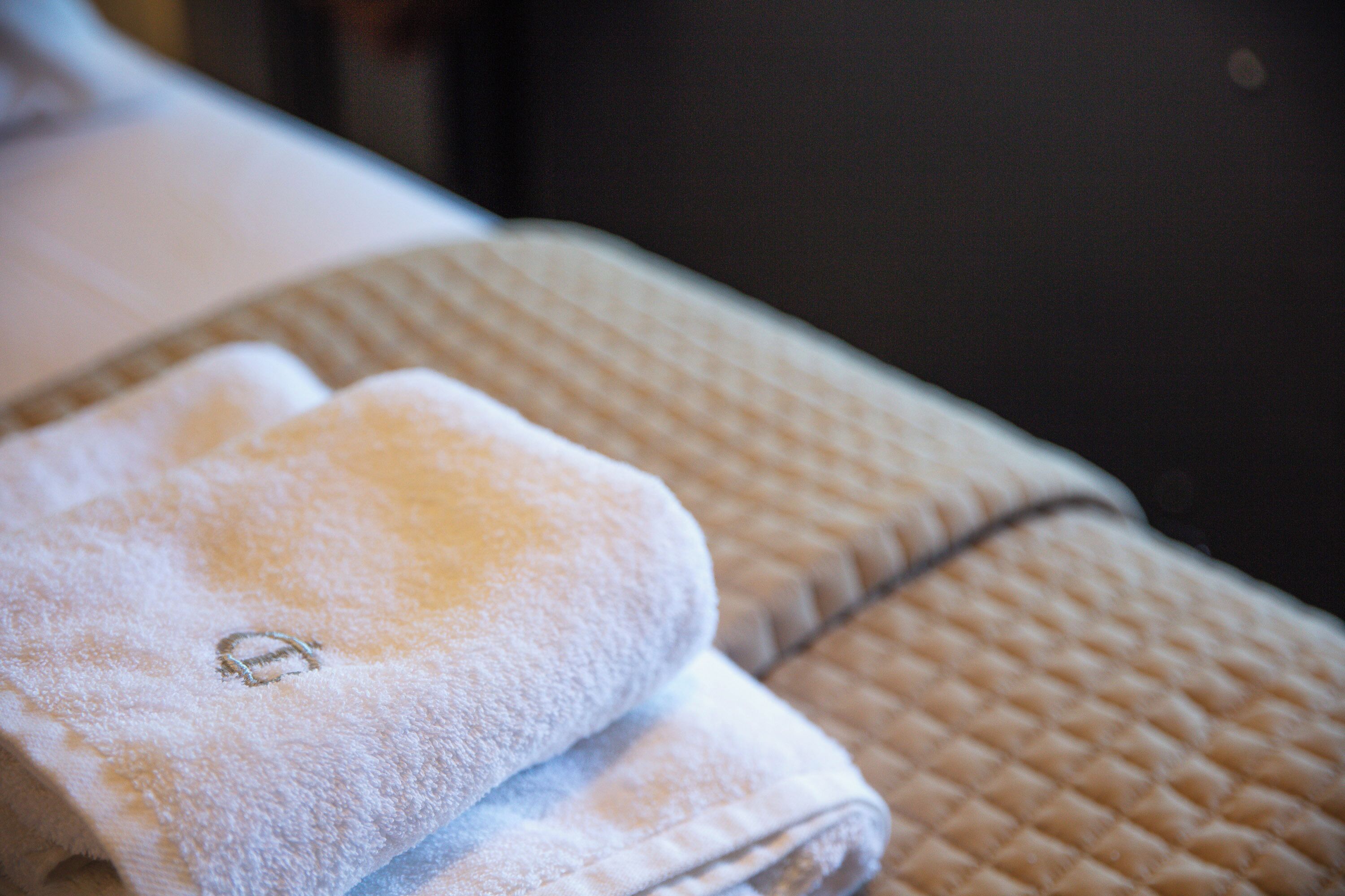 A neatly folded towel on a textured surface, possibly a bed or a bench.