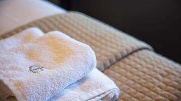 A neatly folded towel on a textured surface, possibly a bed or a bench.