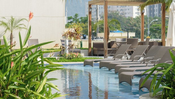 Ein Poolbereich mit Liegestühlen und einer Pergola.