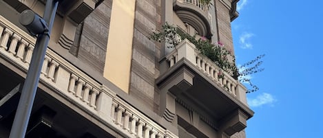 A multi-story building with balconies, columns, and a clear sky.