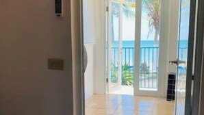 Quarto com cama, porta para varanda vista do oceano.