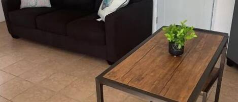 A living room with a dark brown sofa, a wooden coffee table, and a small potted plant.