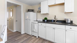 Una cocina compacta con armarios blancos, un microondas, una estufa y un lavabo.