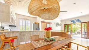 A spacious kitchen with a wooden dining table, chairs, and a hanging light fixture. - Villa Carissa: Private Pool in Seminyak Center, Bali (Bali)