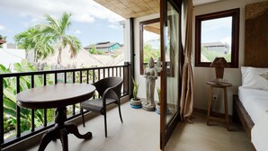 A balcony with a table and chairs, a statue, and a bed with a window view. - Villa Carissa: Private Pool in Seminyak Center, Bali (Bali)