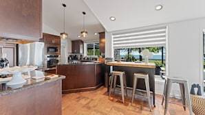 Una cocina moderna con una isla central, electrodomésticos de acero inoxidable y vistas al exterior.