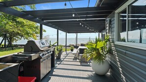 Un patio techado al aire libre con una parrilla, asientos y plantas en macetas.