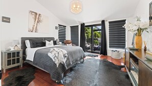 Un dormitorio moderno con una cama grande, una mesita de noche, un aparador y vistas al exterior a través de una puerta corredera.