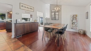 Una cocina amplia con armarios de madera oscura, una isla central y un comedor con mesa de madera y sillas negras.