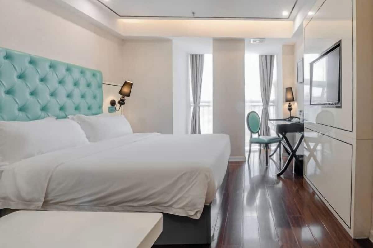 Habitació d'hotel moderna amb un llit gran, una taula de treball i una televisió.