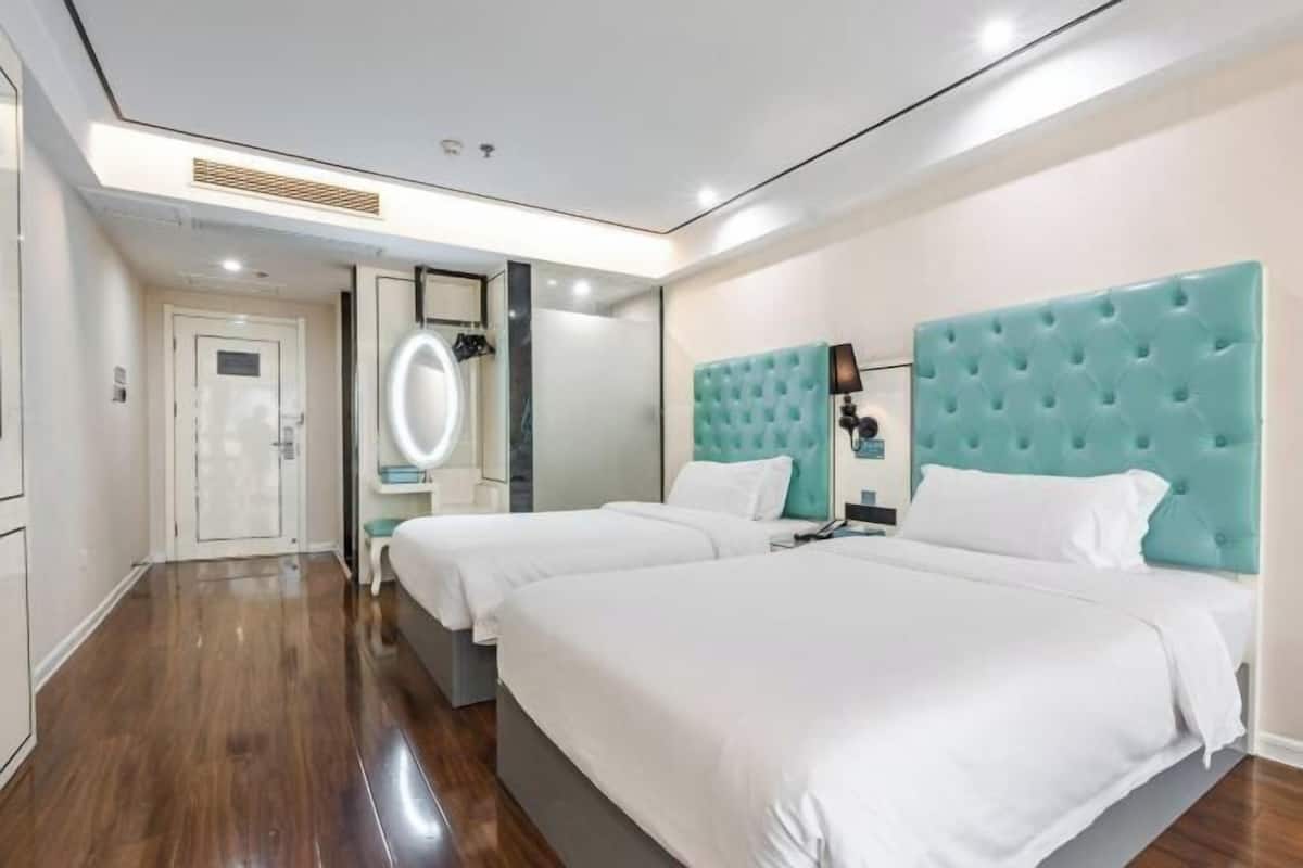 Habitació d'hotel amb dos llits, un mirall, una tocador i una porta que dona a un bany.