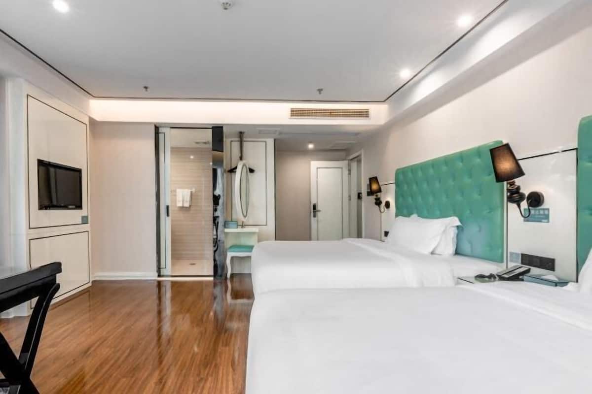 Habitació d'hotel amb un llit, una taula de treball, una televisió i un bany visible a través d'una porta oberta.