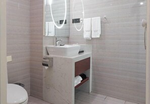 Uma casa de banho moderna com uma pia branca, espelho e suporte para toalhas.