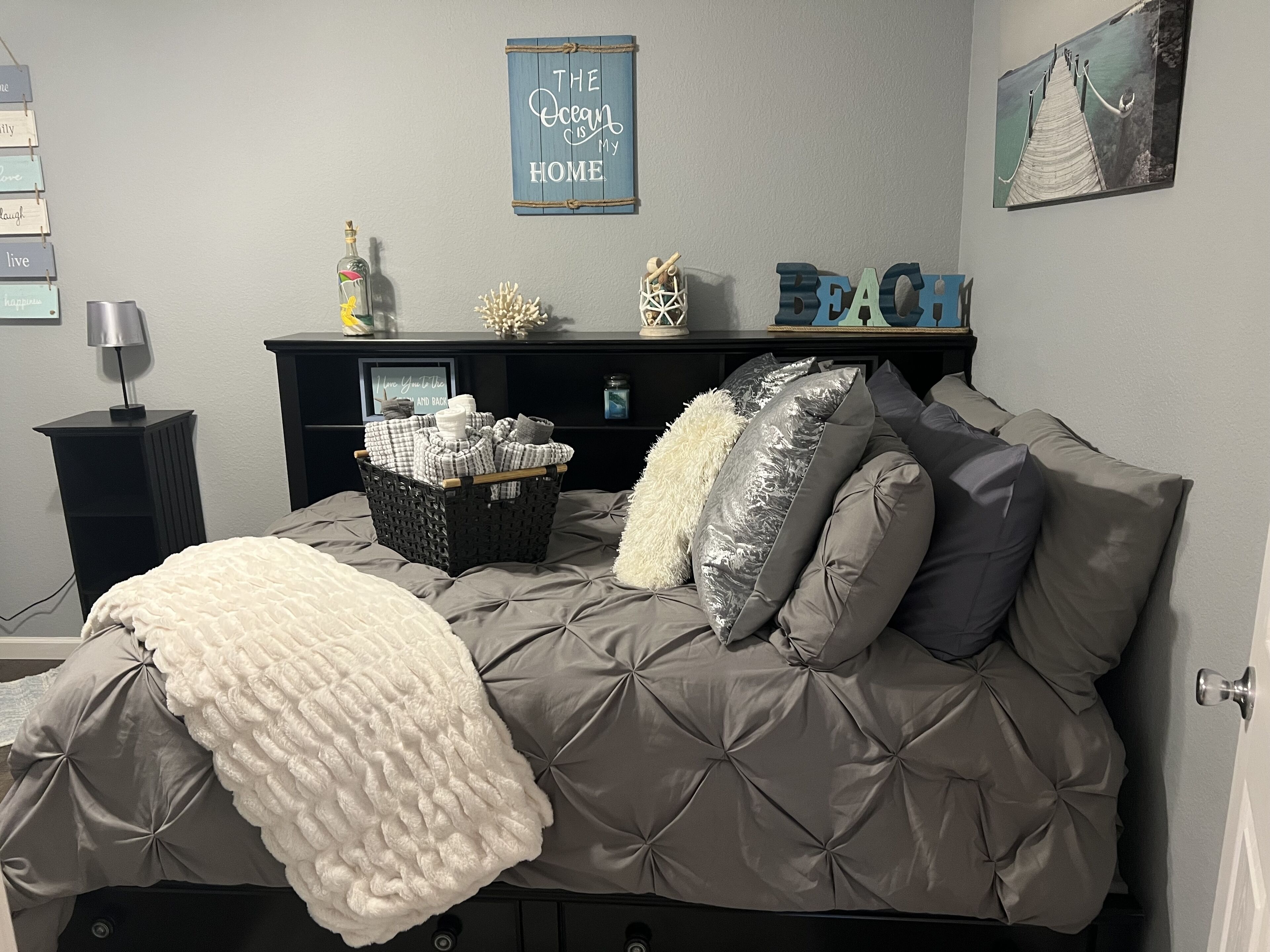 A bedroom with a bed, a dresser, a wall-mounted shelf, and a framed picture.